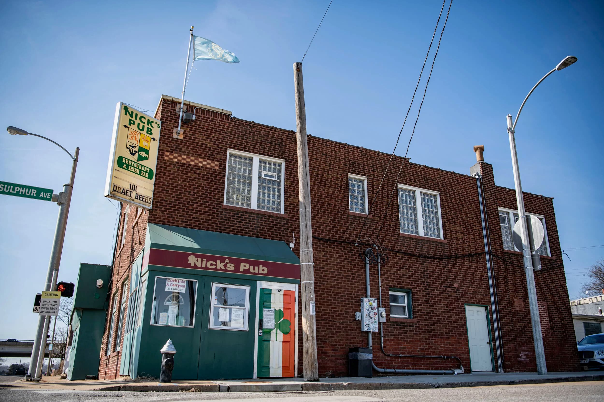 The brick corner building of Nick's Pub with its green sign